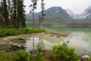 Avalanche Canyon rising above the clear waters of Taggart Lake below smokey skies in the Teton Mountains. Grand Teton National Park, Wyoming