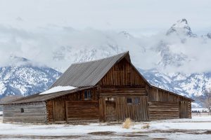 The Moulton Barn standing before the Teton Mountains in snow and clearing fog. Grand Teton National Park, Wyoming