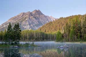 A light fog lifting from Bearpaw Lake reflecting the Teton Mountains above just before sunrise. Grand Teton National Park, Wyoming