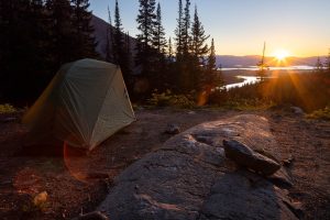 The sun rising over the horizon beyond a backpacking campsite in Paintbrush Canyon of the Teton Mountains. Grand Teton National Park, Wyoming