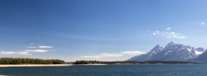 A wide open blue sky dwarfing the Teton Mountains and Jackson Lake along the Lakeshore Trail. Grand Teton National Park, Wyoming