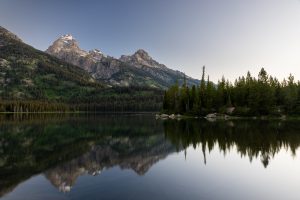 The Teton Mountains reflected in a clear reflection in Taggart Lake before sunrise. Grand Teton National Park, Wyoming