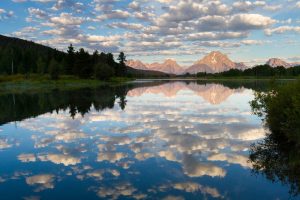 The still waters of Oxbow Bend reflecting Mount Moran and the Teton Mountains as clouds pass overhead. Grand Teton National Park, Wyoming