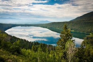 Phelps Lake at the mouth of Death Canyon in Grand Teton National Park, Wyoming reflects clouds in the sky on a still, summer morning.