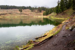 Trout Lake sitting calmly below stormy weather as a light rain falls on its surface. Yellowstone National Park, Wyoming